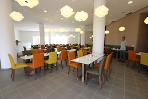 A spacious dining area with multiple tables and chairs, overhead lighting, and a clean, modern interior. - Lunja Village Taghazout (Tamri)