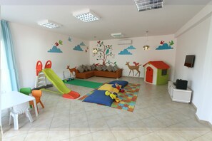 A playroom with a slide, play mats, and a sofa.