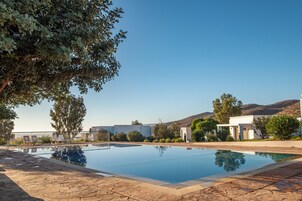 Una piscina con sillas de descanso, rodeada de árboles y edificios.
