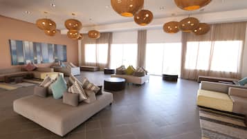 A spacious living area with sofas, a coffee table, and hanging wicker lamps.