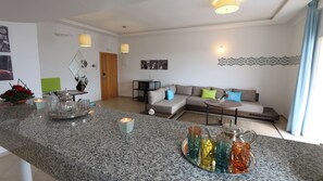 A modern living room with a granite countertop, a sectional sofa, and a small round table. - Lunja Village Taghazout (Tamri)