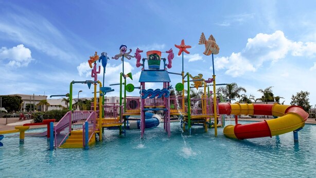 Een waterpark met een speelconstructie, glijbanen en een zwembad.