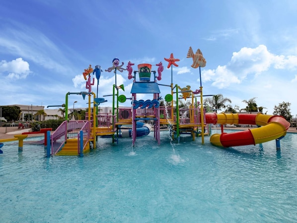 Parque acuático con estructuras de juego, toboganes y una piscina.