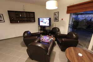 A living room with a TV, leather chairs, a coffee table, and a wooden side table.