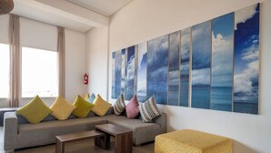 A modern living room with a grey sofa, a wooden coffee table, and a yellow ottoman. - Lunja Village Taghazout (Tamri)