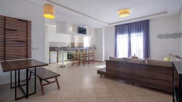 A modern living room with a sofa, a dining table, and a kitchen in the background.