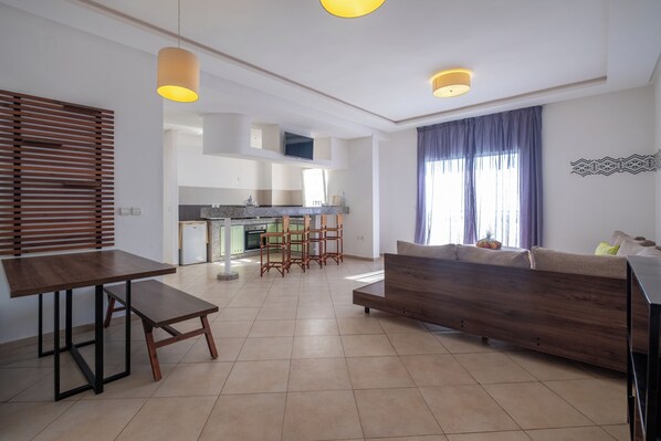 Un salon moderne avec un canapé, une table à manger et une cuisine en arrière-plan.