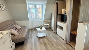 Eine moderne Loft-Wohnung mit Schlafgalerie, einer kleinen Essecke, einer Küchenzeile und einem großen Fenster, das für natürliches Licht sorgt.