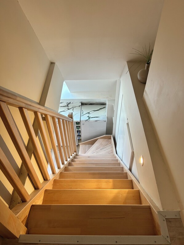 A wooden staircase with a handrail leading to a landing.