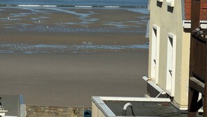 Ein Küstenblick mit Strand, einem kleinen Boot und einem Gebäude mit geneigtem Dach und Fenstern.
