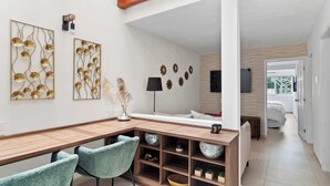 A modern living room with a wooden dining table, teal chairs, and decorative wall art.