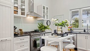 Une cuisine moderne avec des meubles blancs, une cuisinière, un four et un coin repas comprenant une table et des chaises.