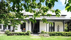 Un bâtiment blanc doté d’un porche abrité, de volets noirs et d’une grille en fer forgé décorative.