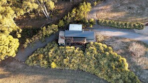 Vue aérienne d’une maison entourée d’une végétation luxuriante et bordée d’un chemin de gravier.
