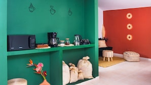 A green kitchen area with a microwave, coffee maker, and storage bins. - Bohemia Boutique Hostel (Cali)