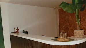 A reception desk with a wooden panel design, a potted plant, and a tray with items on it. - Bohemia Boutique Hostel (Cali)