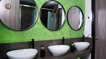 Un baño con tres espejos redondos, dos lavamanos y una toalla colgada en la puerta.