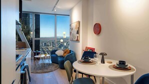 Un espace de vie moderne comprenant un coin repas, un canapé et une vue sur le paysage urbain grâce à de grandes fenêtres.