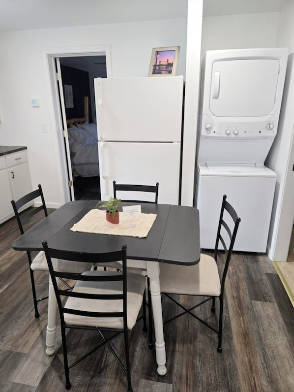 Une cuisine compacte comprenant une table à manger, des chaises, un réfrigérateur et un lave-linge.