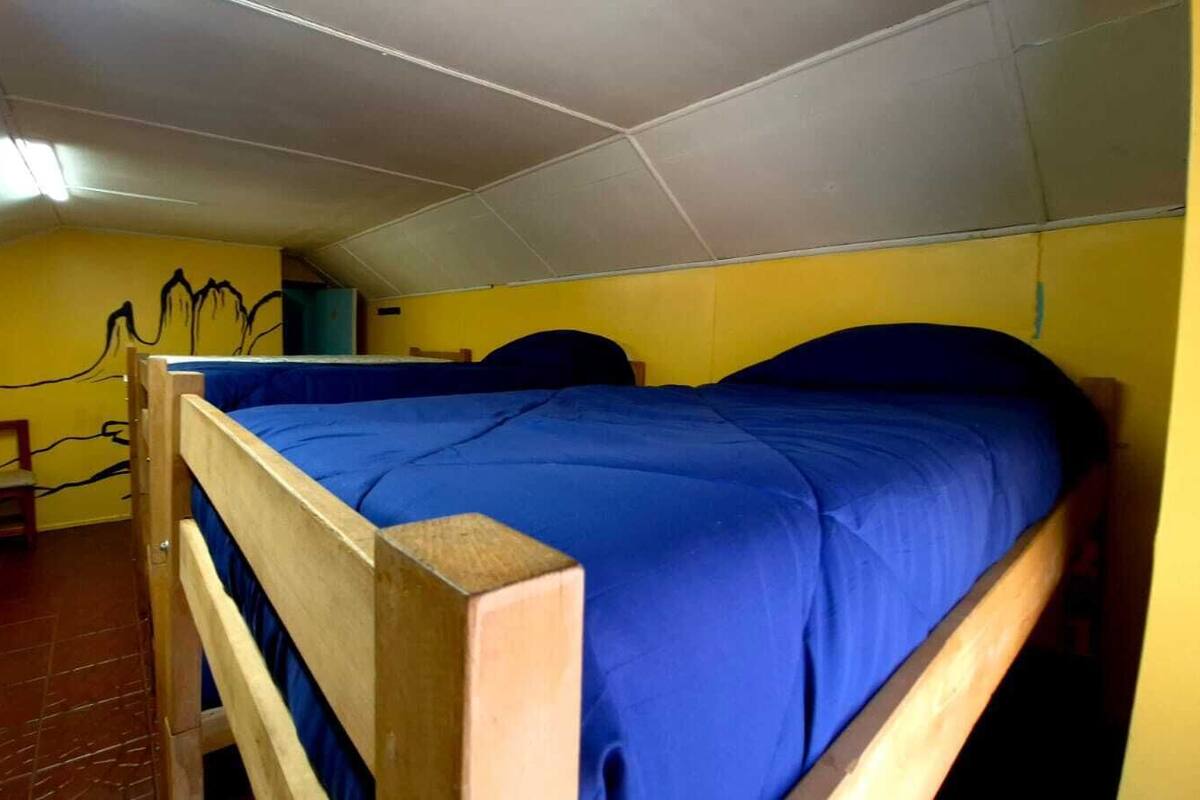 Un dormitorio con literas, una silla de madera y un mural en la pared.