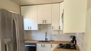 A modern kitchen with white cabinets, stainless steel appliances, and a wooden countertop. - Charming 1-bedroom duplex house in Berkeley (Berkeley)