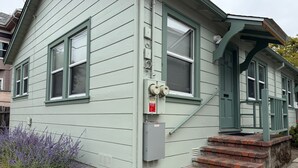 A two-story house with a green exterior, a front porch, and a brick staircase leading to the entrance. - Charming 1-bedroom duplex house in Berkeley (Berkeley)