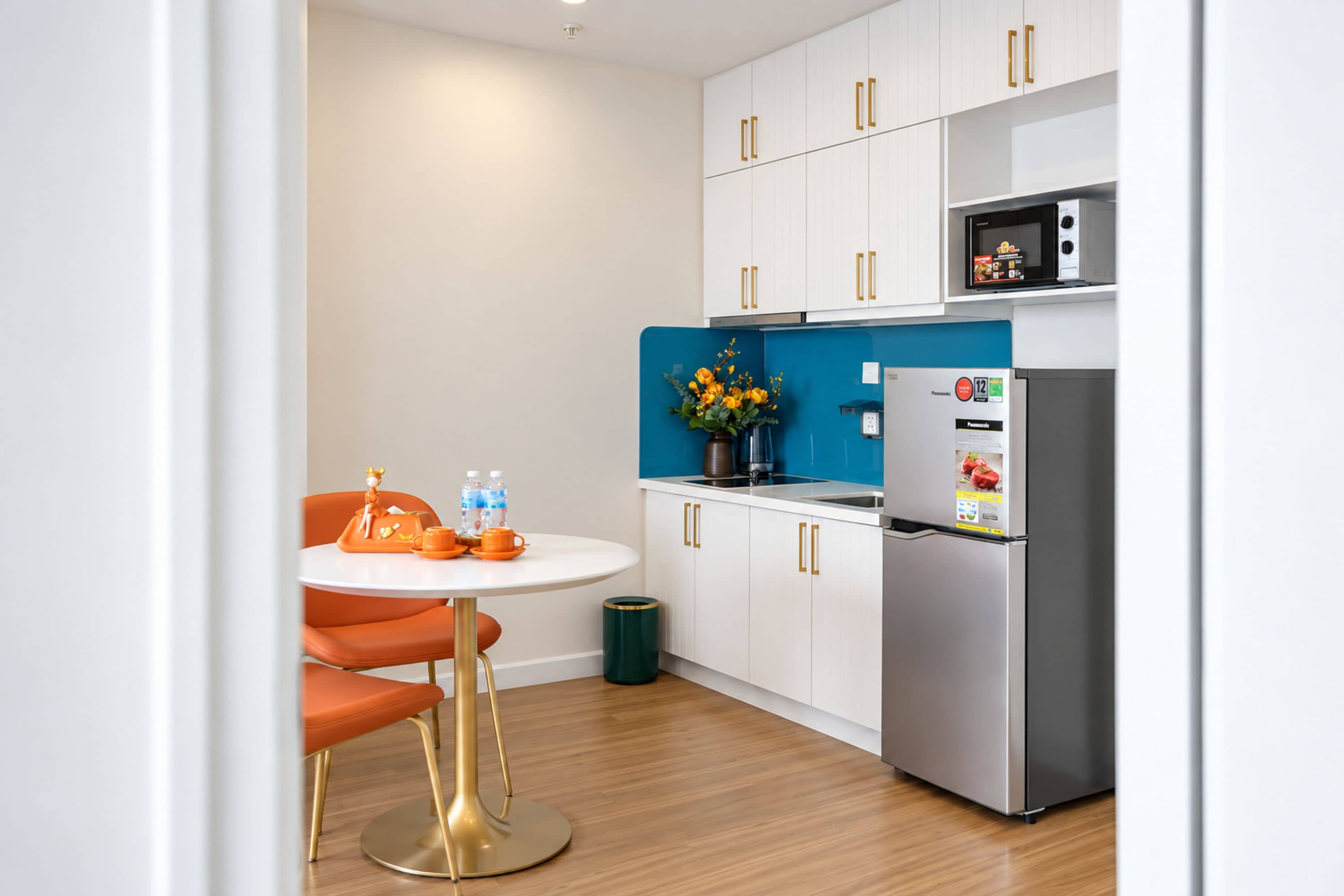 A modern kitchen with white cabinets, a stainless steel refrigerator, and a blue backsplash.