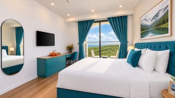 Una camera da letto moderna con un letto grande, una scrivania, una sedia, una TV e un balcone con vista panoramica.