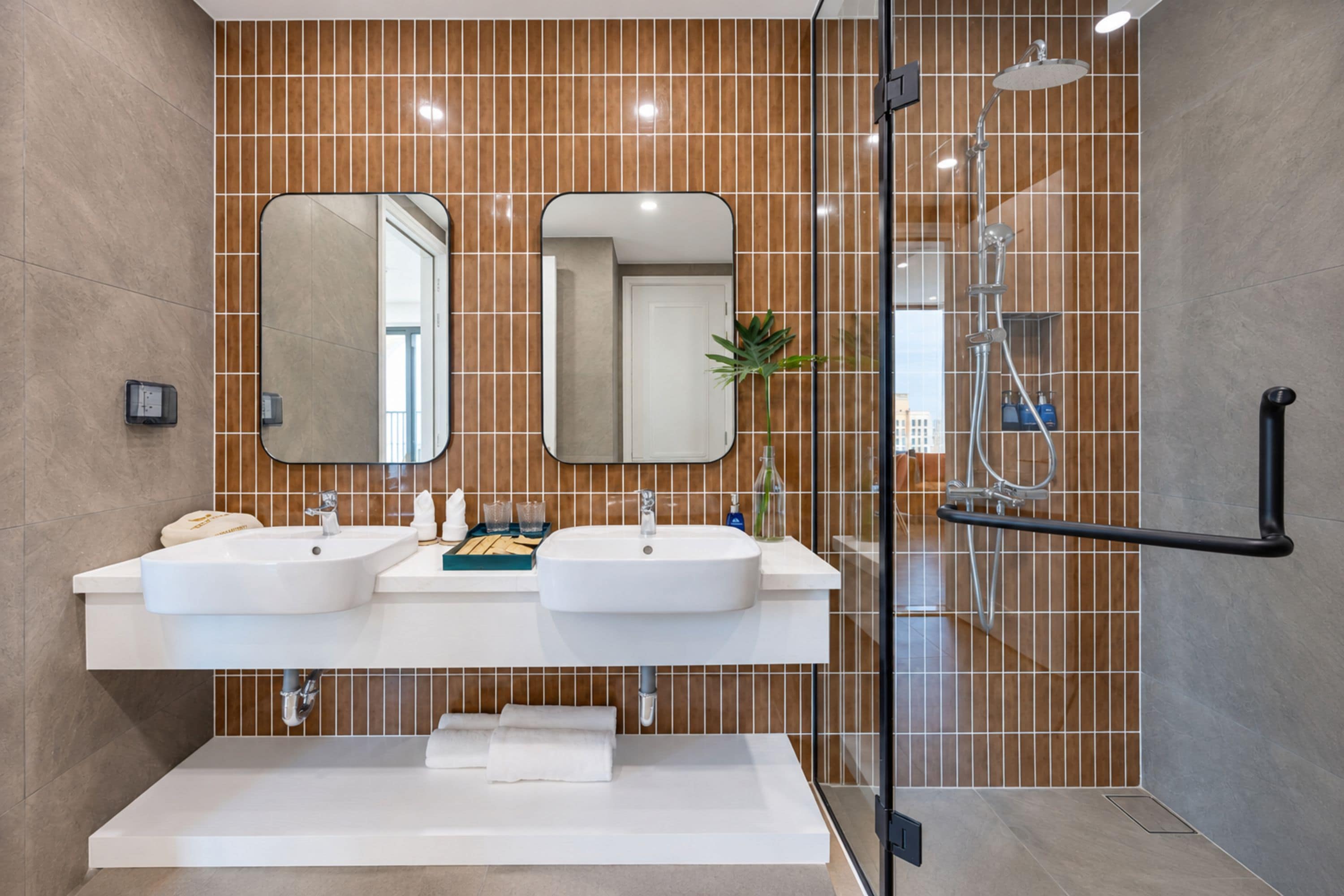 A modern bathroom with two sinks, a shower, and a glass-enclosed shower area.