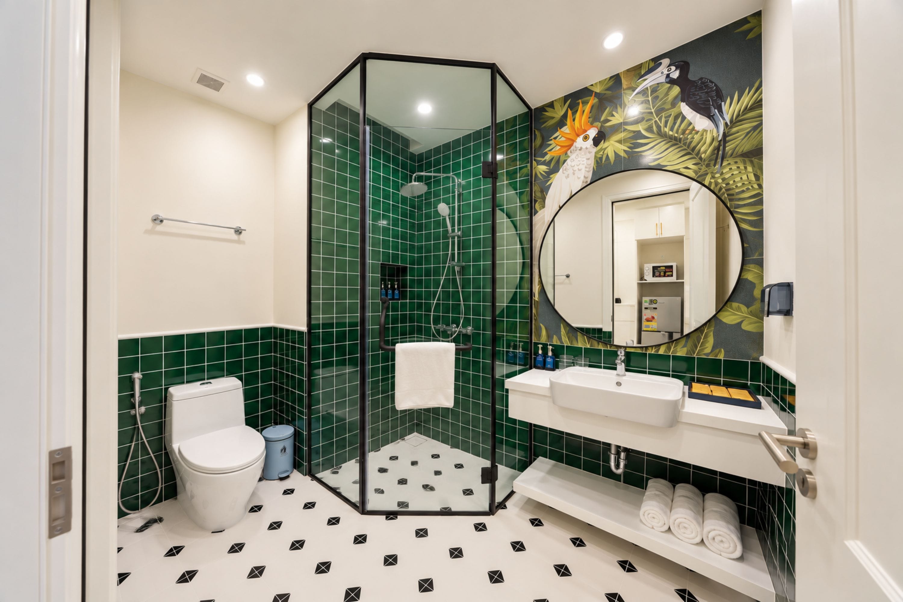 Un baño con ducha de vidrio, inodoro, lavabo con espejo y repisa con toallas.