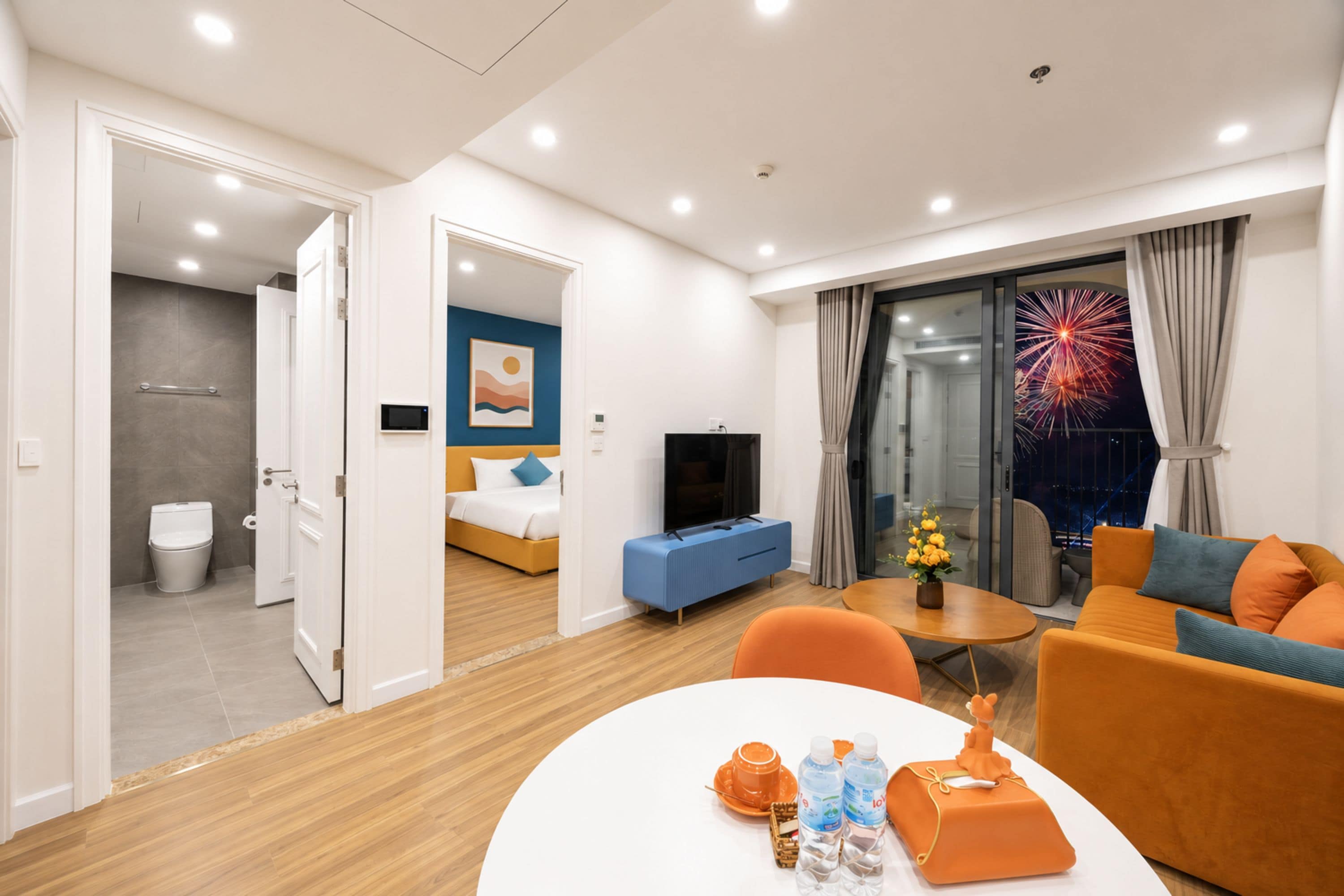 A modern hotel room with a bed, a TV, a sofa, and a dining table.