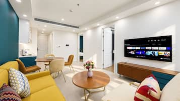 Una sala de estar moderna con un sofá amarillo, una mesa de centro redonda y un televisor de pantalla plana montado en la pared.