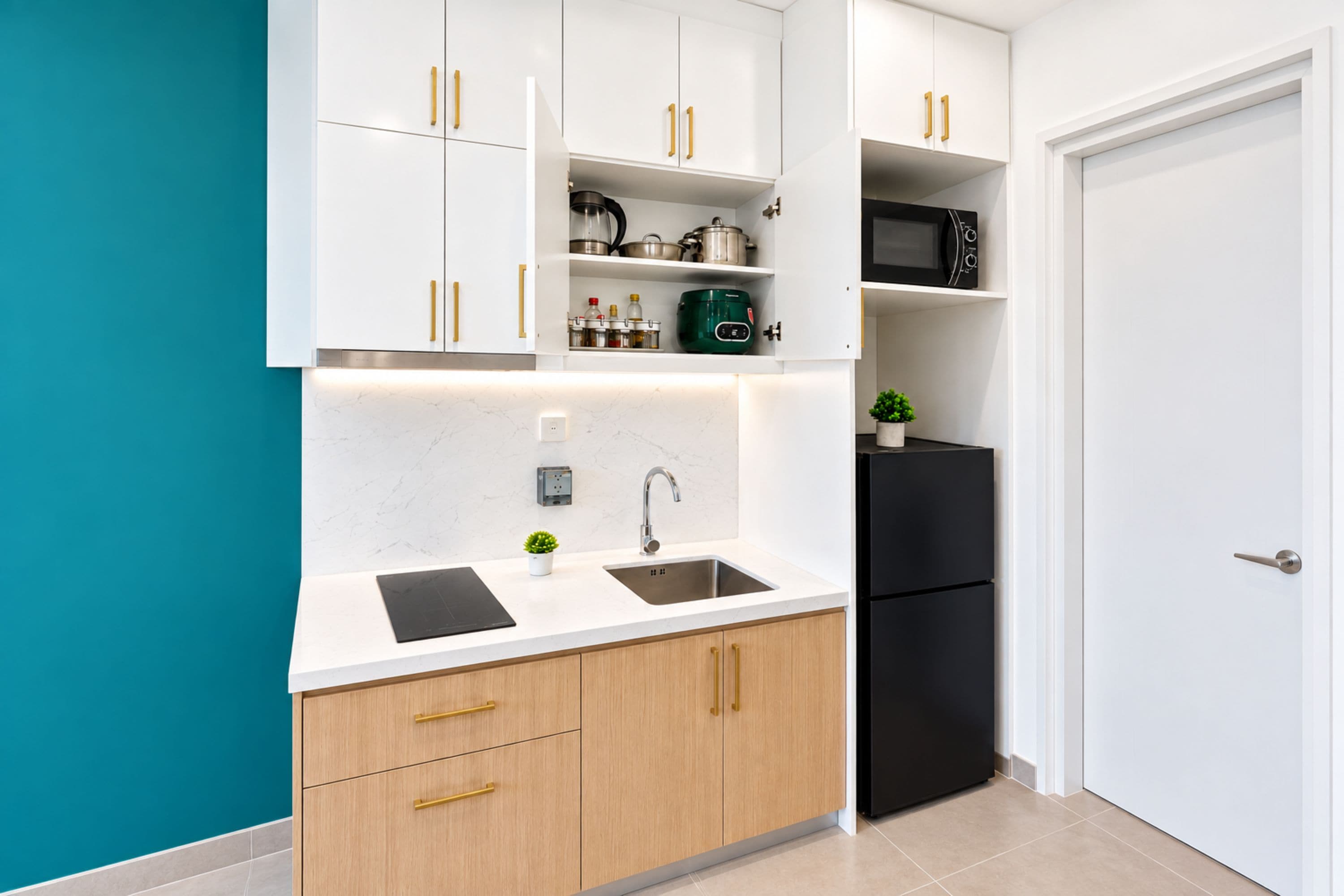 A modern kitchen with white cabinets, a black refrigerator, and a stainless steel sink.