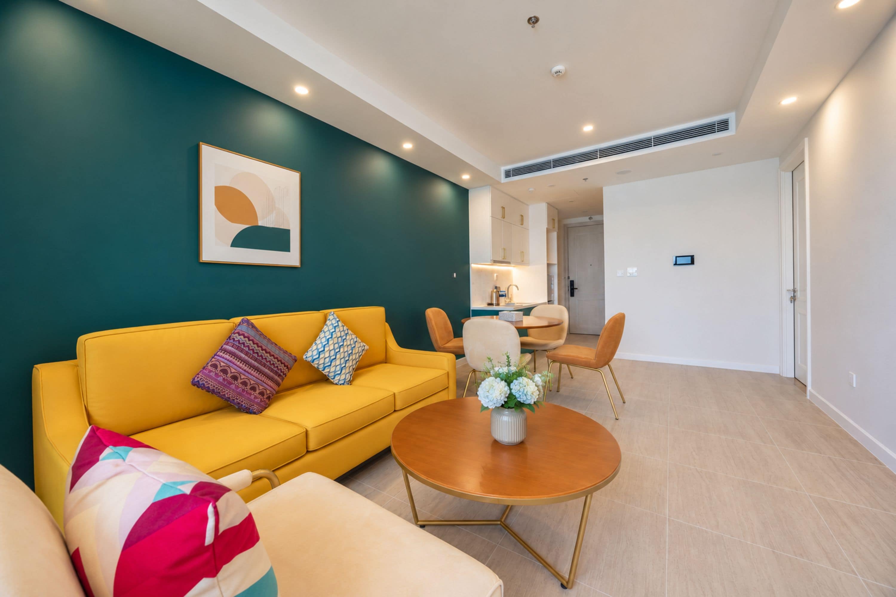 Uma sala de estar moderna com um sofá amarelo, uma mesa de centro redonda e um quadro na parede.