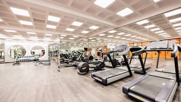 A modern gym with treadmills, elliptical machines, and free weights.