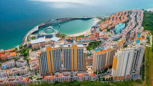 An aerial view of a coastal residential area with high-rise buildings, a marina, and a bridge. - Skywave Apartment Firework Delight (Phu Quoc)