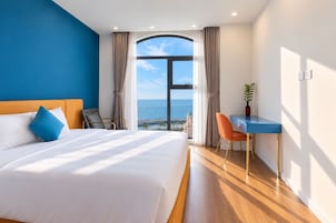 Una habitación de hotel con una cama grande, un escritorio y vistas al mar.
