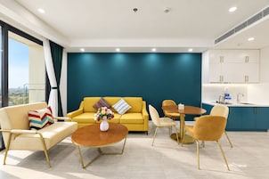 Una sala de estar moderna con un sofá amarillo, una mesa de centro y una zona de comedor con sillas.
