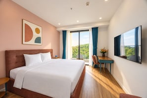 A hotel room with a large bed, a desk, a chair, and a TV. - Skywave Apartment Firework Delight (Phu Quoc)