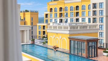 A swimming pool with a glass enclosure, surrounded by yellow buildings with multiple balconies.