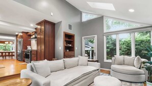 A modern living room with a sofa, ottoman, and a dining area with a table and chairs. - Sojourn Beautiful Home with Beach Access & Backyard (Falls Church)