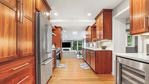 A modern kitchen with wooden cabinets, stainless steel appliances, and a wooden floor. - Sojourn Beautiful Home with Beach Access & Backyard (Falls Church)