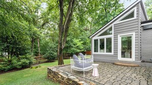 A patio with a stone wall, a white metal chair, and a small table. - Sojourn Beautiful Home with Beach Access & Backyard (Falls Church)