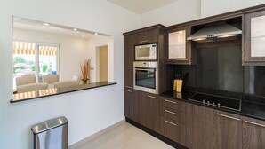 Une cuisine moderne avec des meubles en bois foncé, des appareils électroménagers en acier inoxydable et un plan de travail noir.