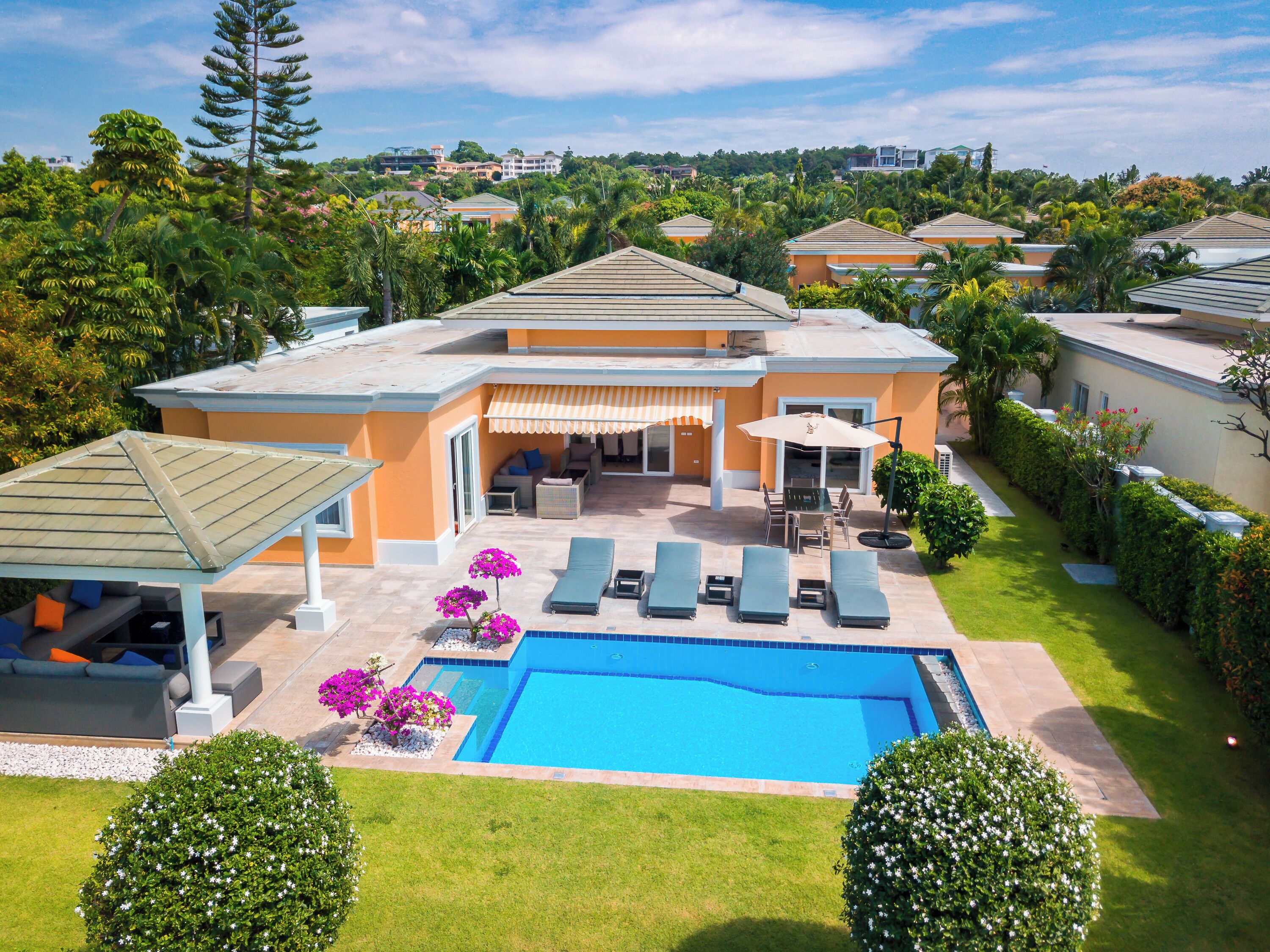 A residential property with a swimming pool, outdoor seating, and a covered patio area.