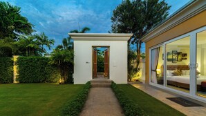 Une maison moderne, avec un chemin menant à une porte, entourée d’une végétation luxuriante.