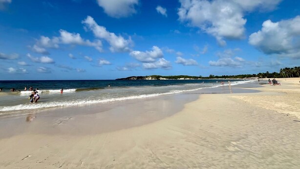 A wide sandy beach with clear blue water and scattered clouds. - Newly renovated condo in El Cortecito in Punta Cana, Dominican Republic! (Punta Cana)