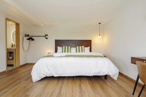 A neatly made bed with a wooden headboard, a bedside table, and a hanging towel rack.