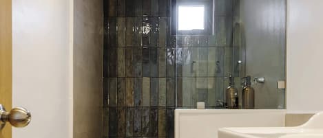 A bathroom with a glass shower enclosure, a white toilet, and a wooden vanity with a sink.