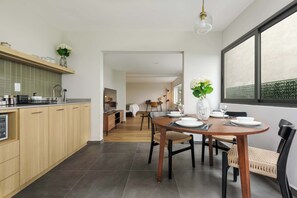 A modern kitchen with wooden cabinets, a dining area with a round table, and a large window.